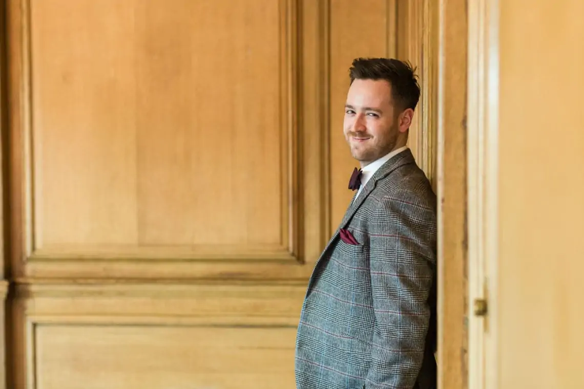 Groom leaning against panelled wood wall in the Boardroom