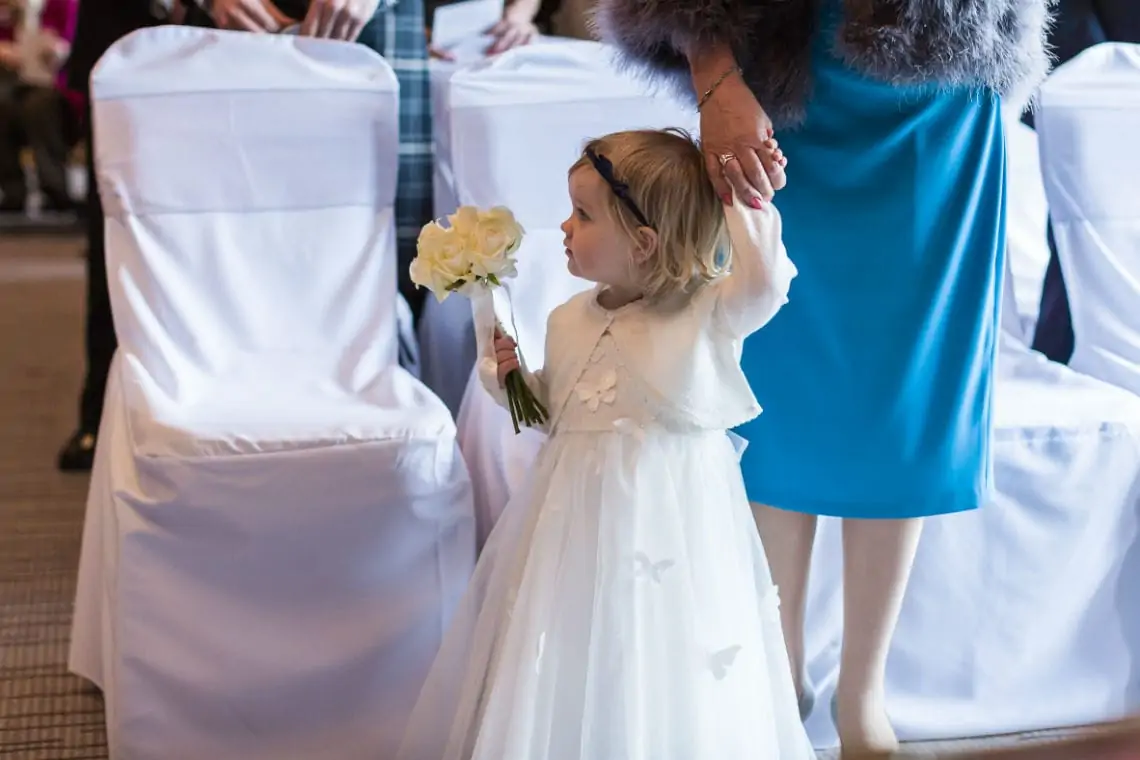 Young little Flower Girl holding posy of flowers in the Boardroom
