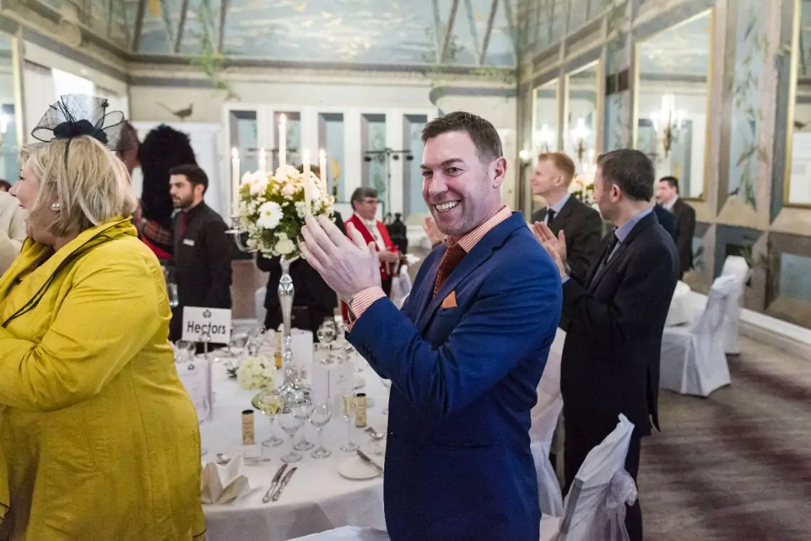 Man clapping as newlyweds make their entrance to the top table