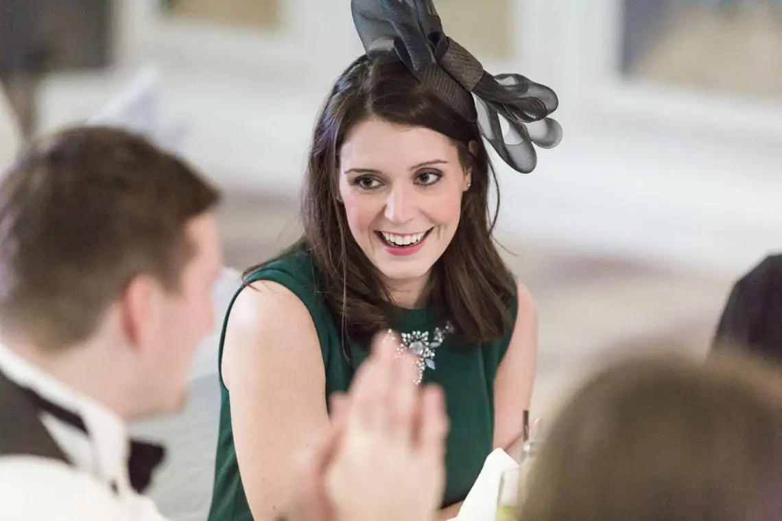 Lady wearing a green dress and fascinator smiling