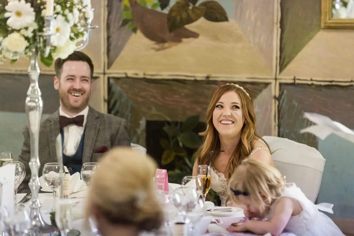 Bride and Groom sitting at top table laughing during speeches