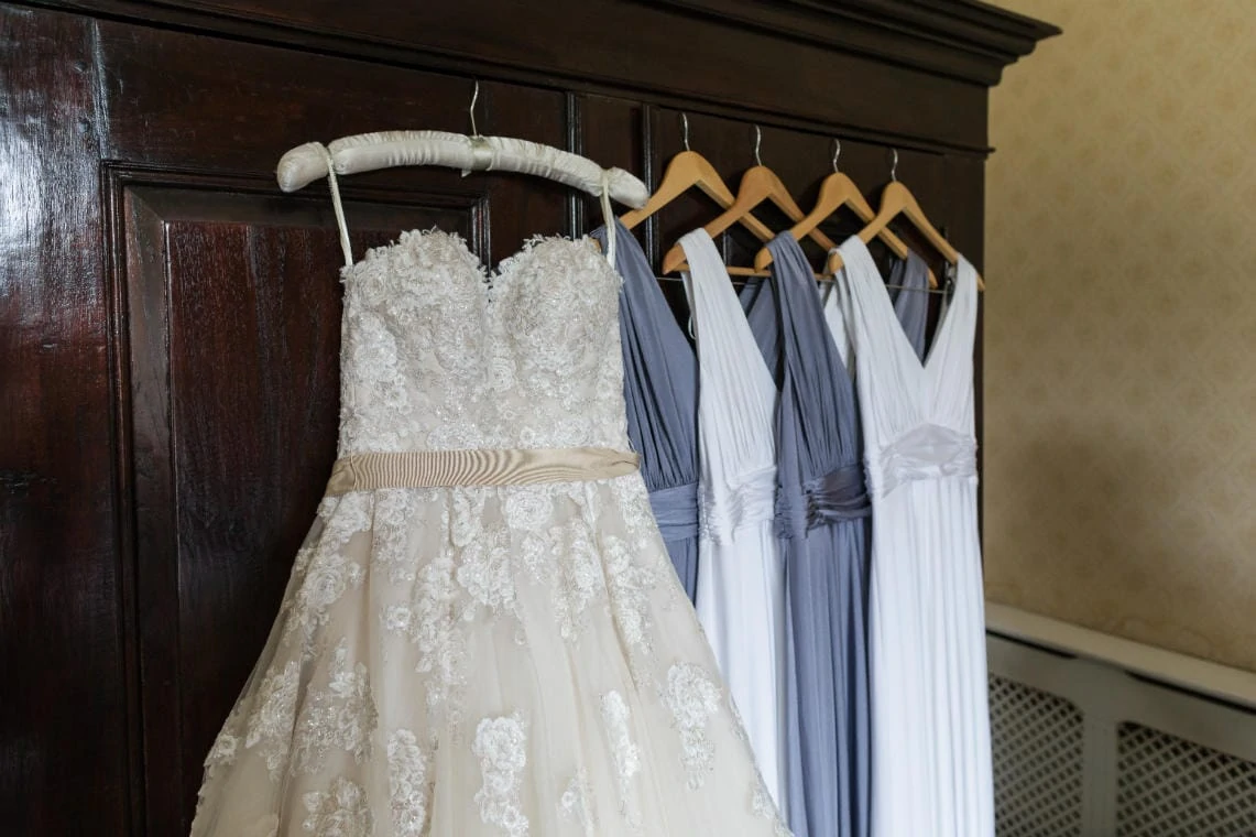 photo of bride and bridesmaid's dresses hanging up on a wardrobe
