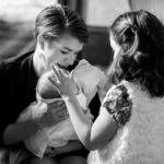 black and white photo of lady holding baby and little girl touching baby's head
