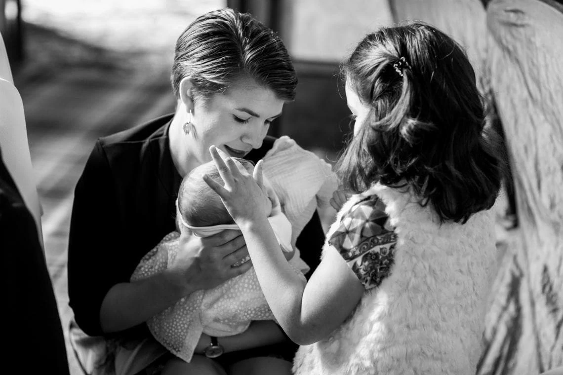 black and white photo of lady holding baby and little girl touching baby's head