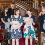 photo of ladies from bridal party walking down the aisle holding twin babies