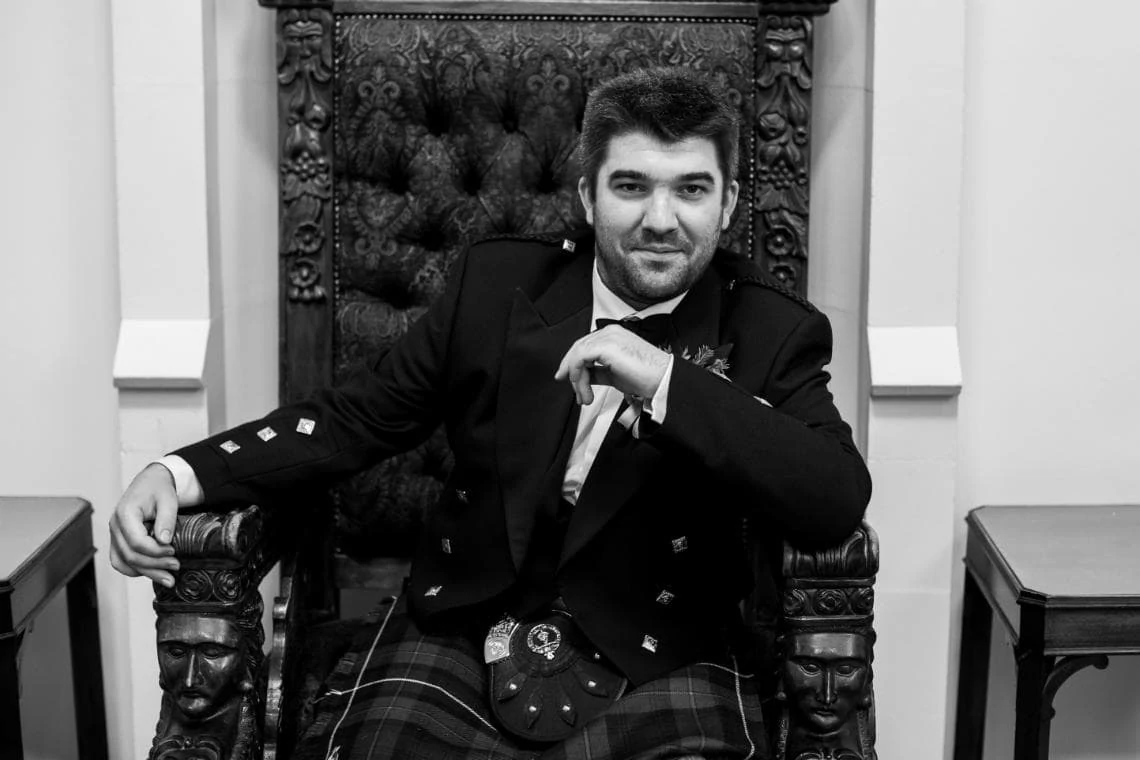 Wedding at Dalhousie Castle posed photo of groom sitting on chair