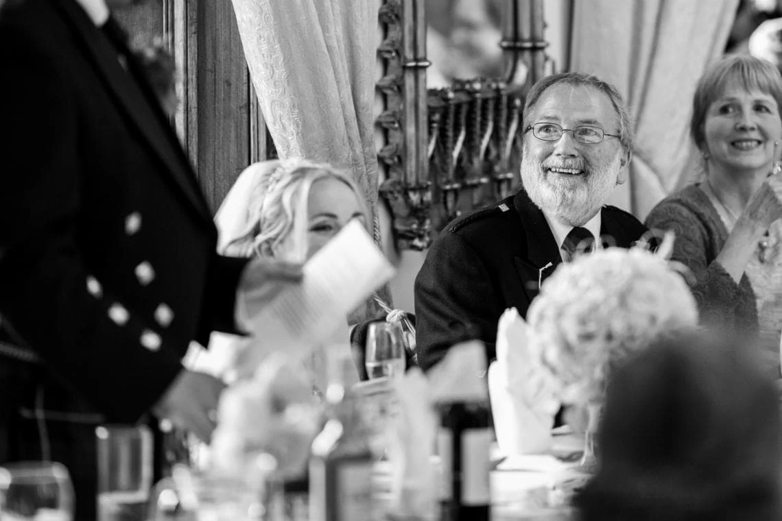 father of the bride smiling during speeches at wedding reception