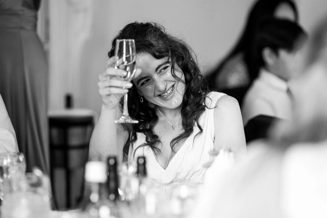 bridesmaid raising her glass during a toast at wedding reception