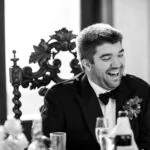 groom laughing during speeches at wedding reception