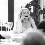 bride laughing at top table during speeches at evening reception