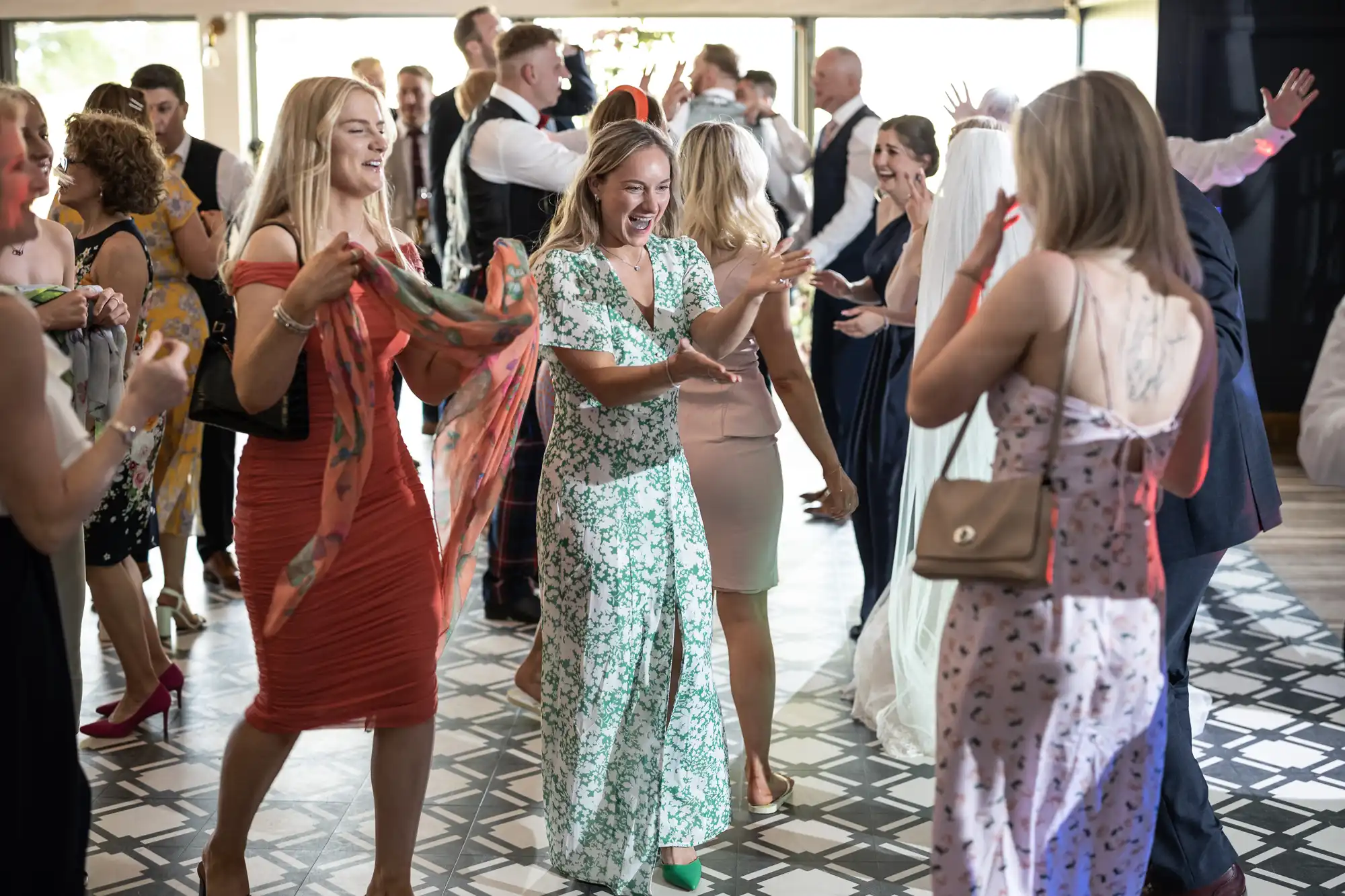 A group of people joyfully dancing at a festive indoor event, with streamers in their hands and smiling faces.