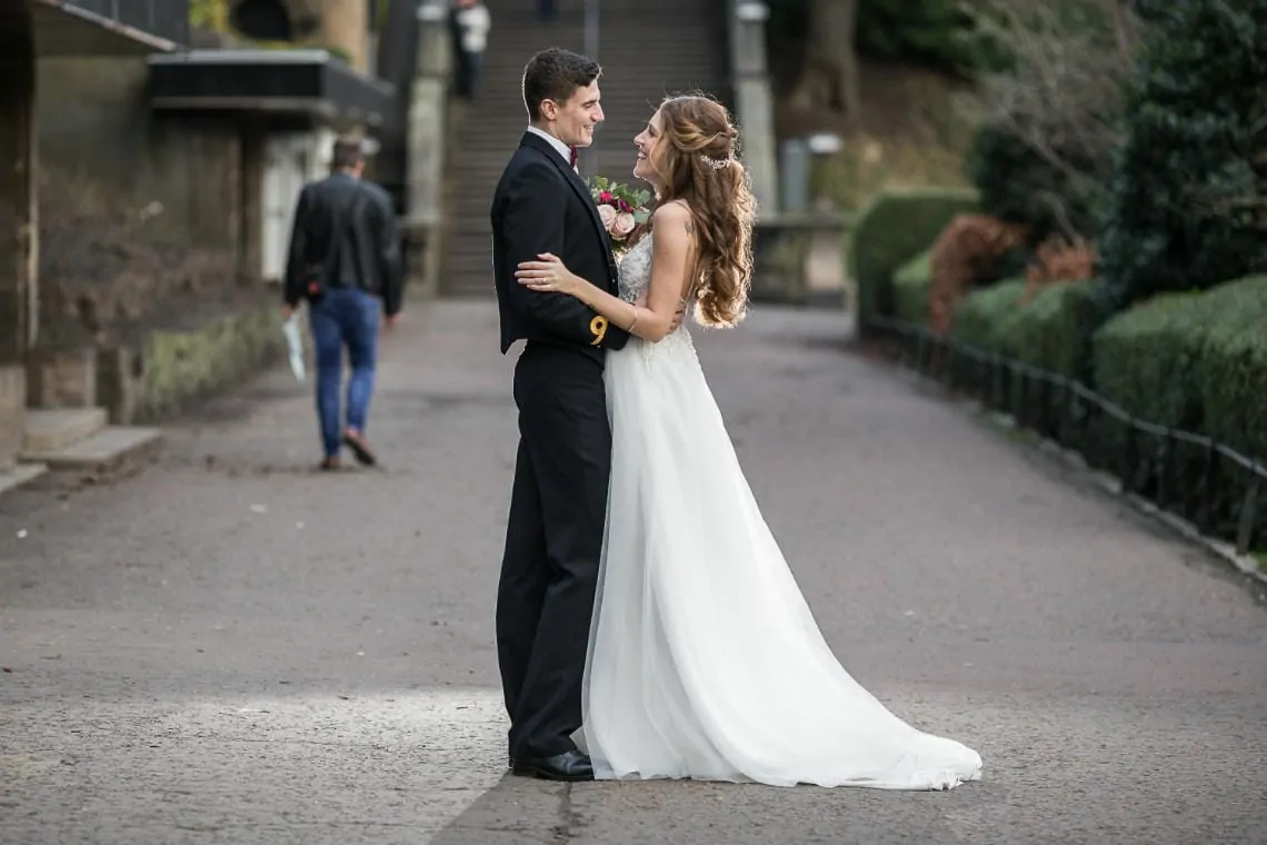 newlyweds embrace in Princes Street Gardens