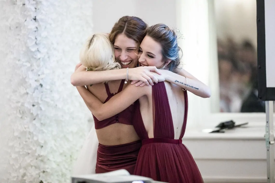 bride embraces the bridesmaids after they deliver their speech in the King's Hall