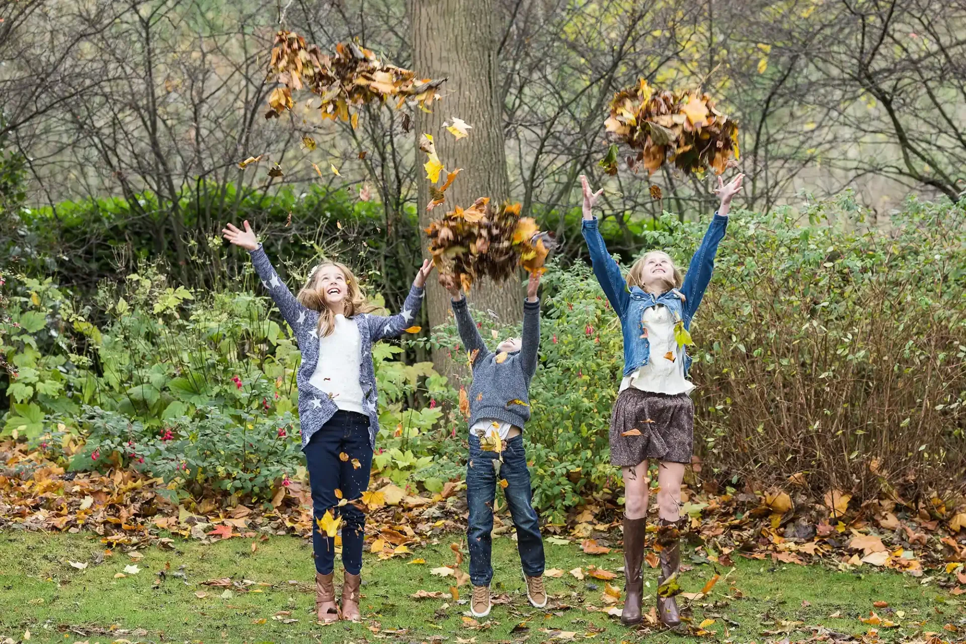 kids throwing autumn leaves in Princes Street Gardens - Family photographer in Scotland