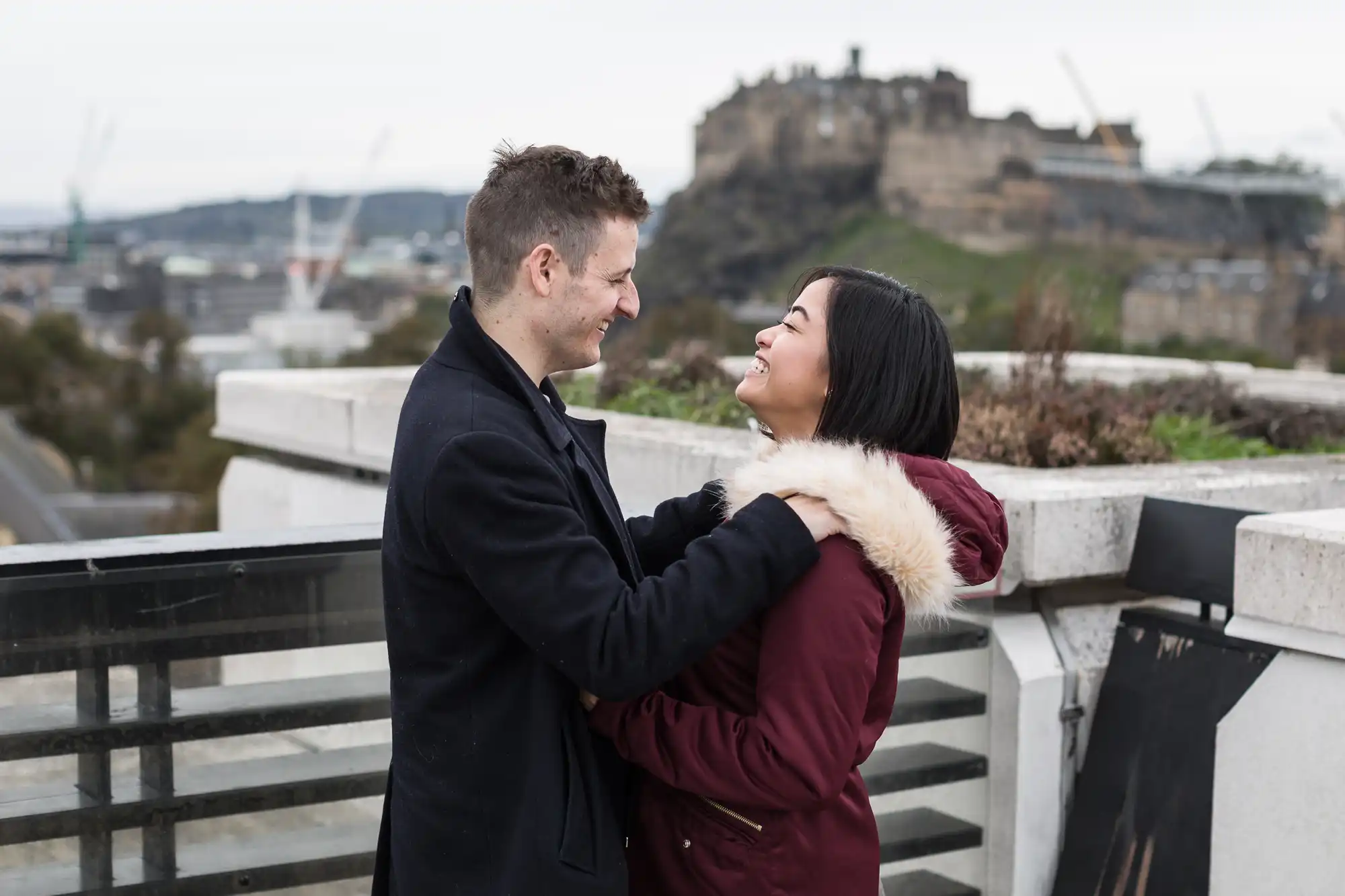 A couple affectionately looking at each other with edinburgh castle in the background.