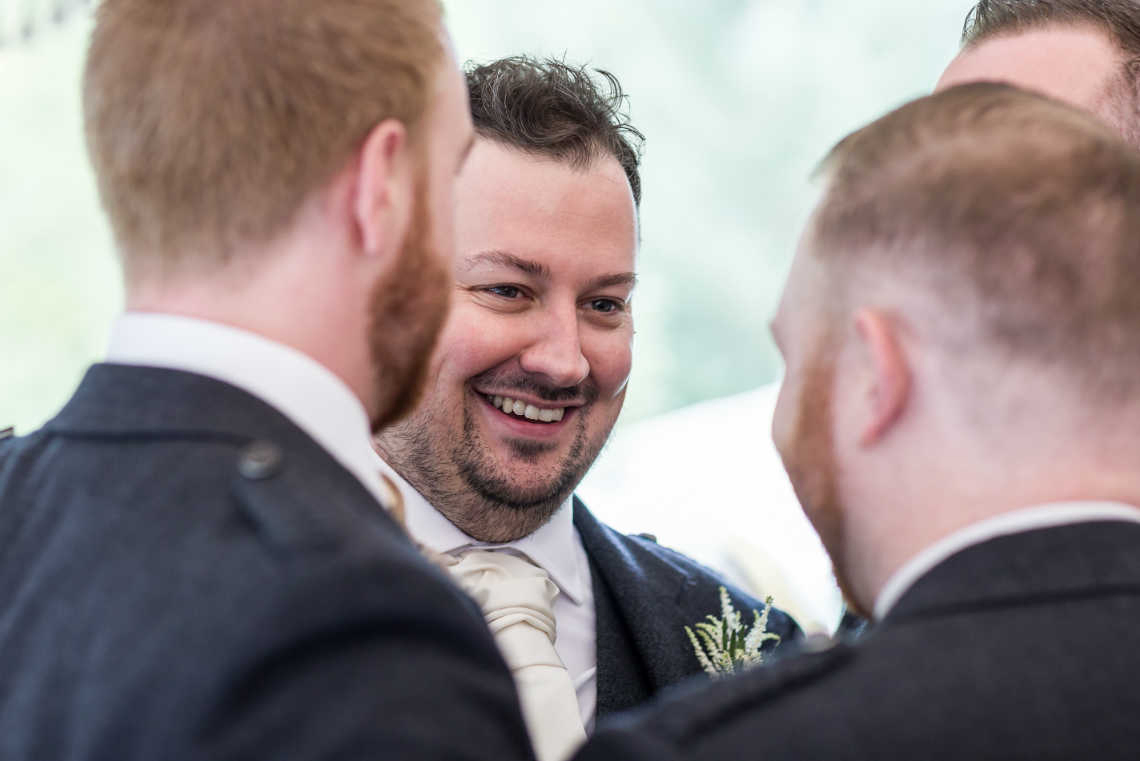 groom laughs with best man and groomsmen