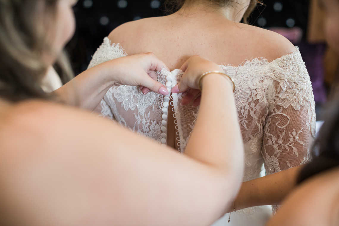 bridesmaids help button up back of bride's dress