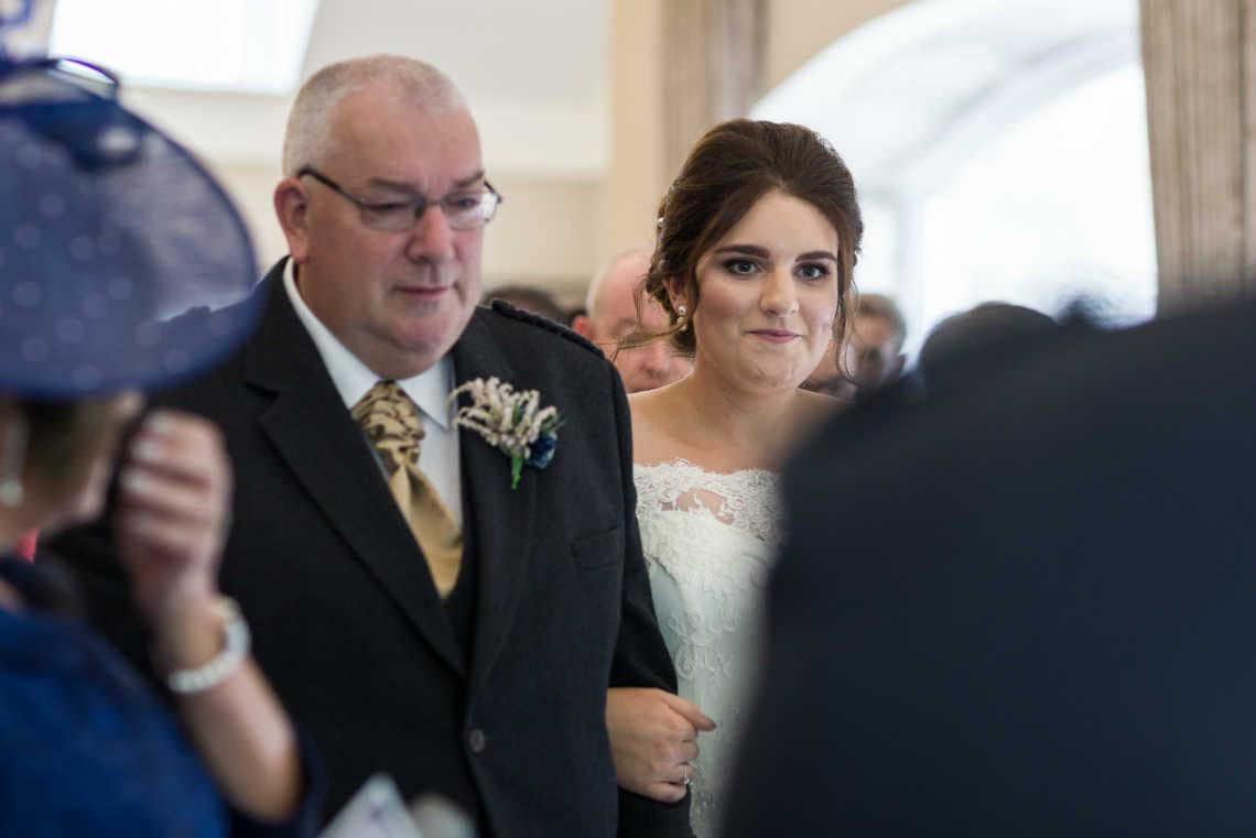 father and bride walk up the aisle during wedding processional