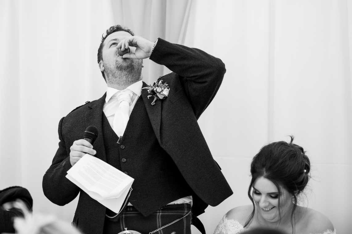 groom necks a shot during his speech