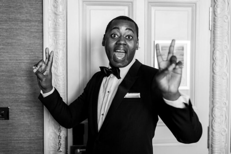 happy groom wearing a black suit and bow tie