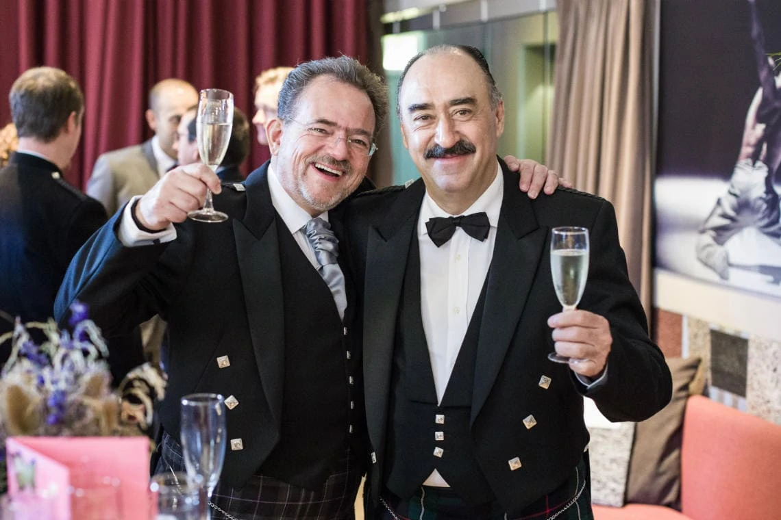Celebration cheers photo of two men wearing Scottish Highland outfits
