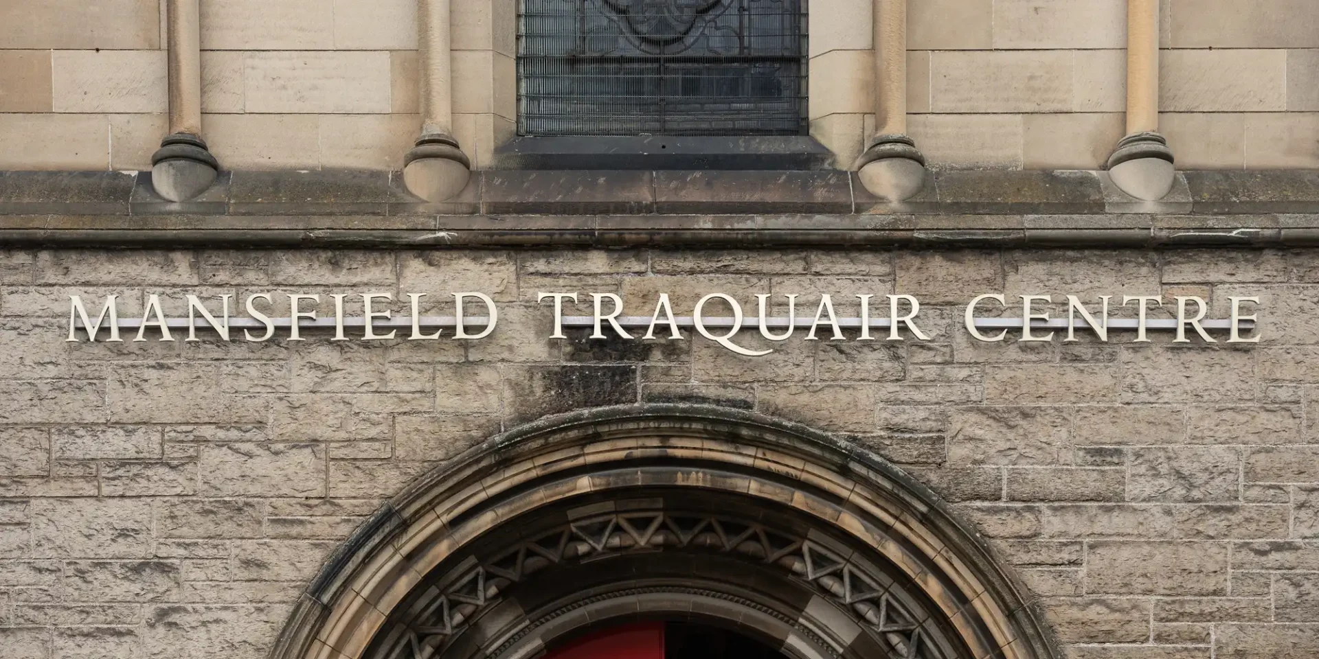 Facade of the Mansfield Traquair Centre, featuring stone brickwork and an arched window above the entrance.