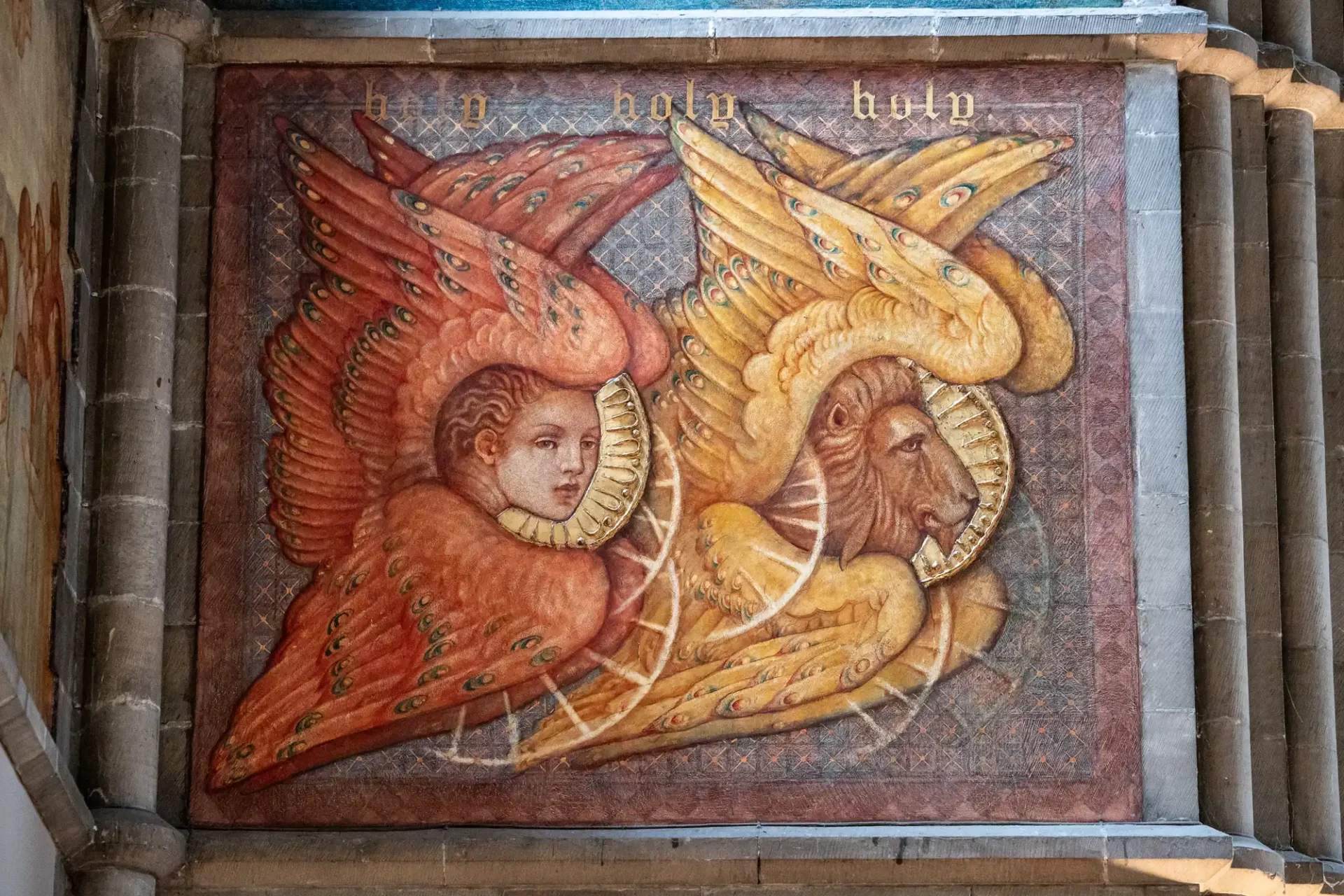 Painting with a human head and a lion head, both with wings and haloes, on a wall. The words "holy holy holy" are above them.